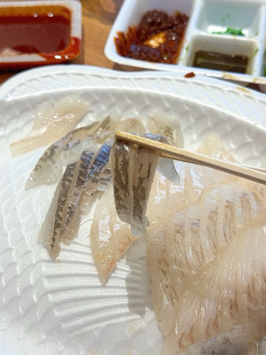 Chopsticks picking up two pieces of dab sashimi