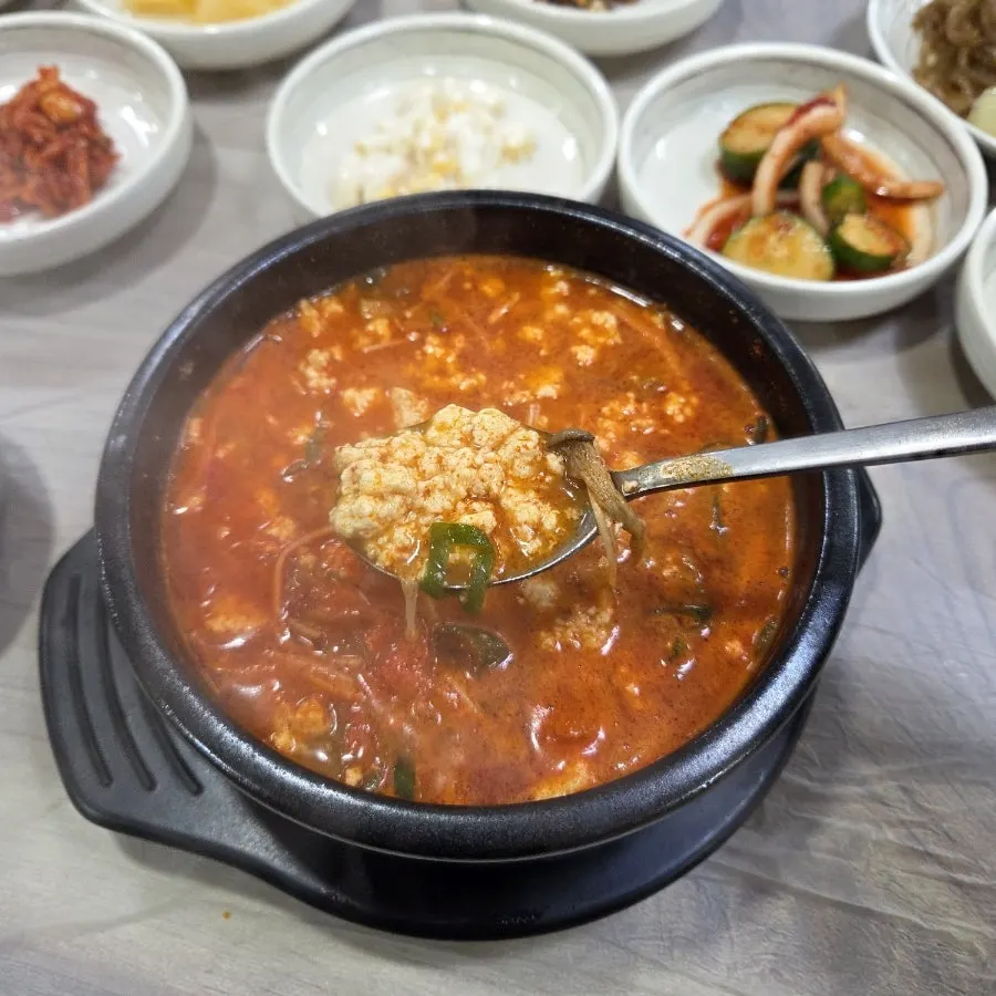 A spoonful of soft sundubu lifted from the pot