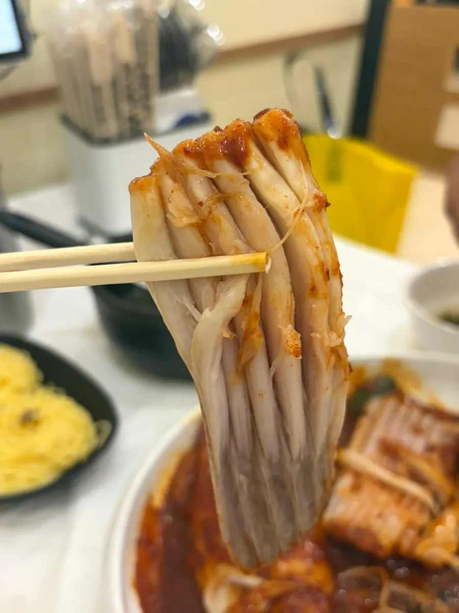 Close-up of the steamed skate meat pulling apart along the grain