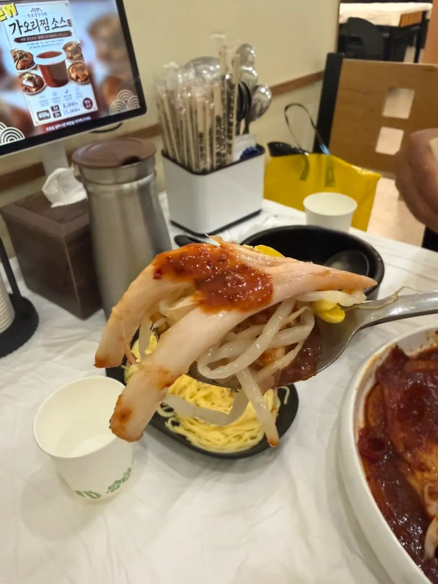 A spoonful of rice topped with skate meat and sauce