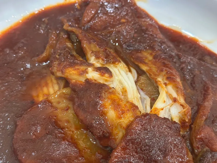 Skate flesh revealed beneath the sauce