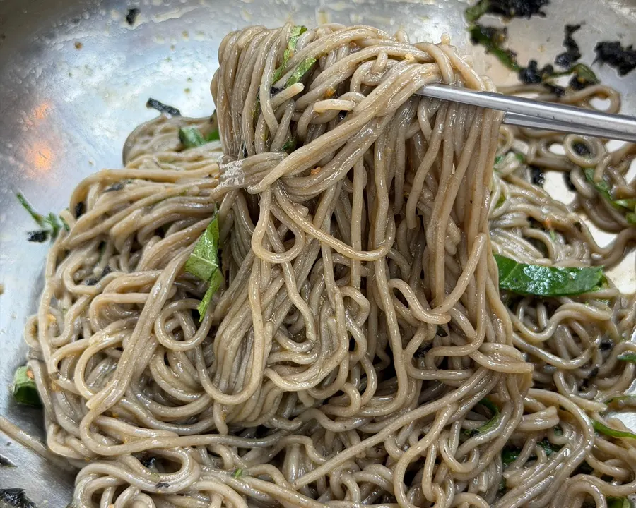 Perilla oil makguksu topped with seaweed flakes and perilla leaves