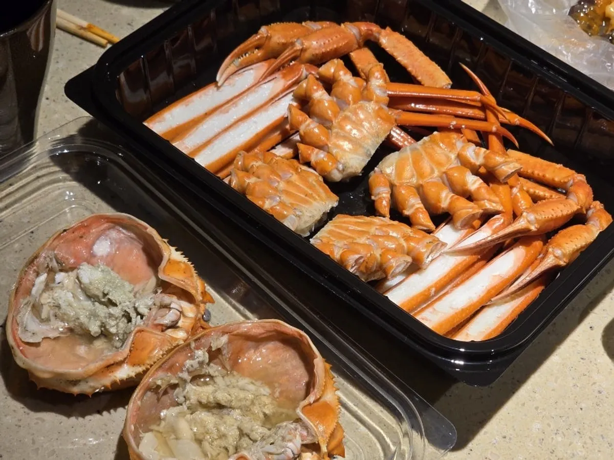Two red snow crabs with meat already picked in the lunchbox