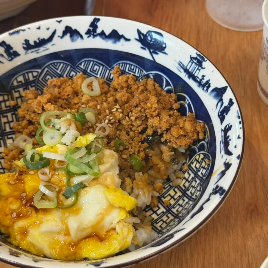 Close-up of butadon with meat, egg, and green onion toppings over rice