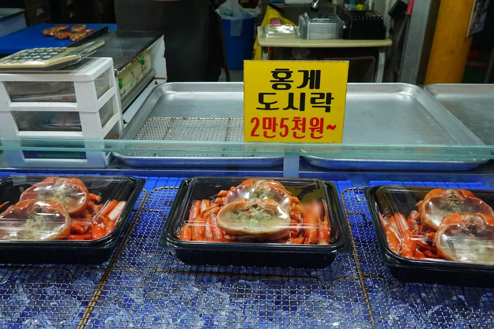 Red snow crab lunchboxes and rice balls displayed over ice