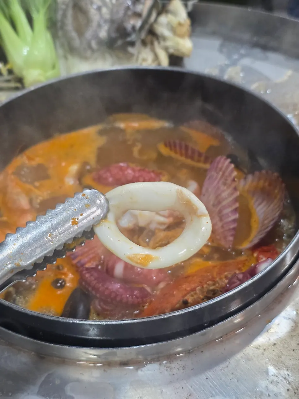 A plate of cooked seafood lifted out of the pot