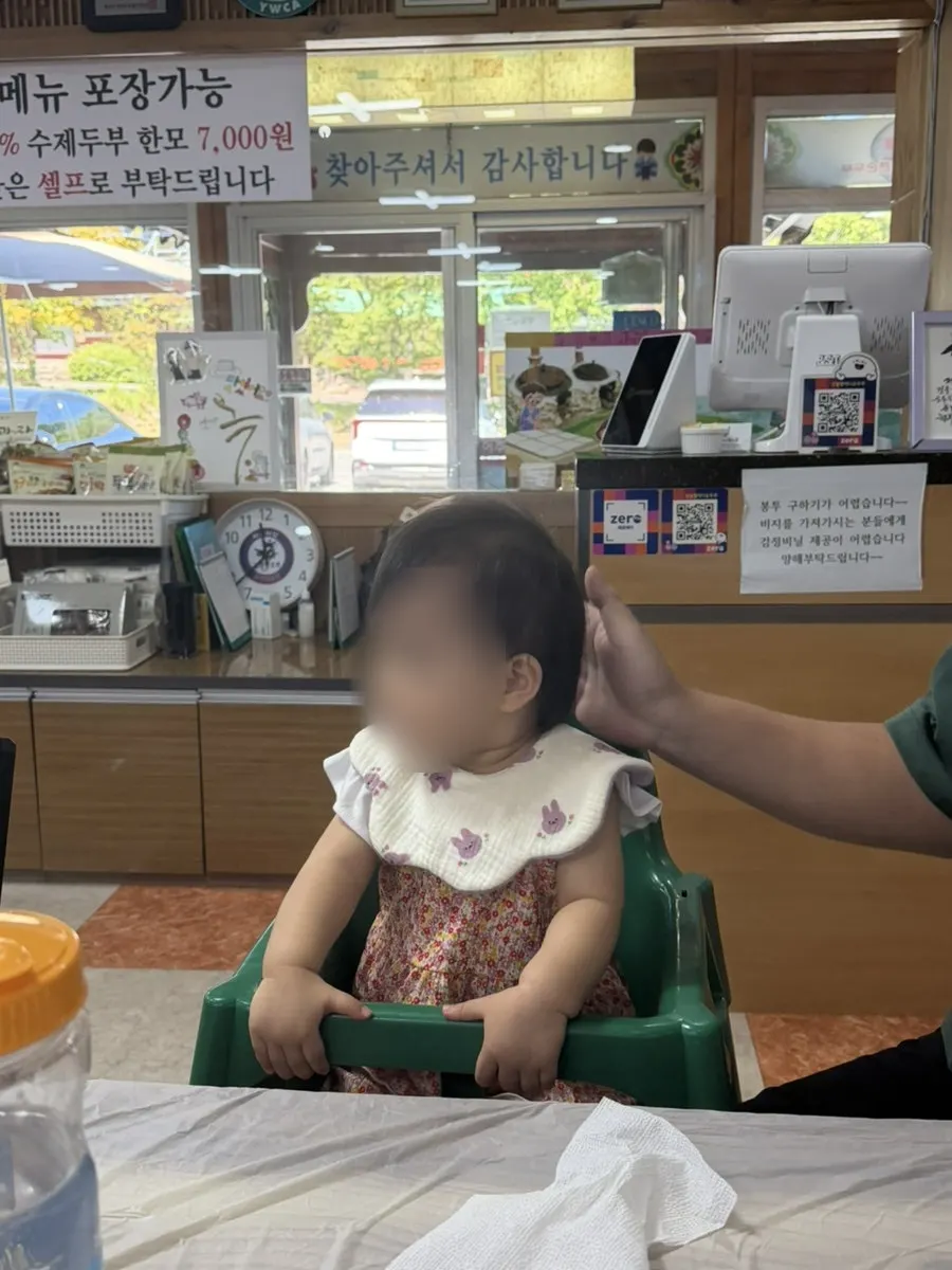 A baby sitting in a baby chair eating a meal
