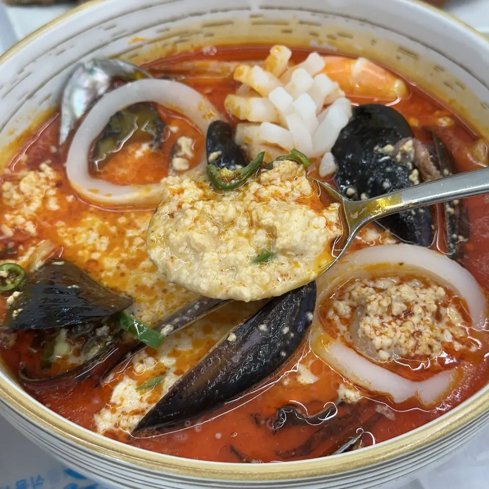 A clear, white bowl of chodang sundubu