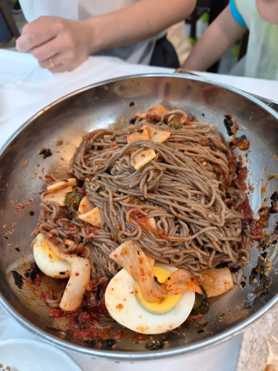 A bowl of pollack sashimi makguksu with seasoning added