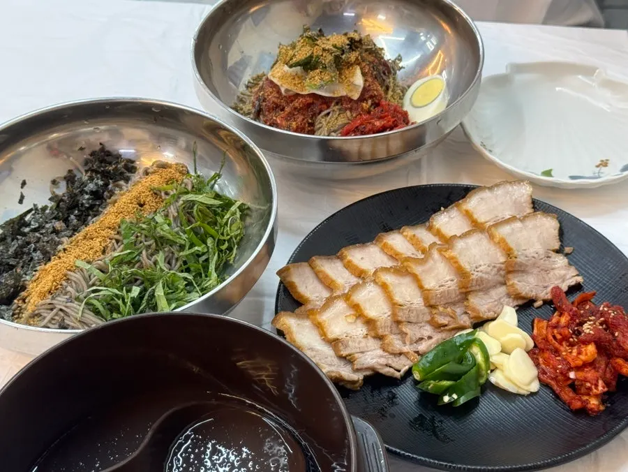Table spread of deulmemak, pollack sashimi buckwheat noodles, and solo suyuk