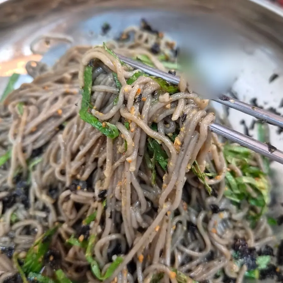 Perilla oil makguksu topped with perilla leaf, perilla seeds, and seaweed
