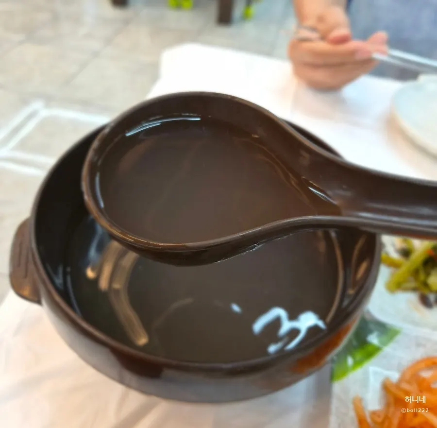 Dongchimi broth poured into a paper cup alongside potato pancake
