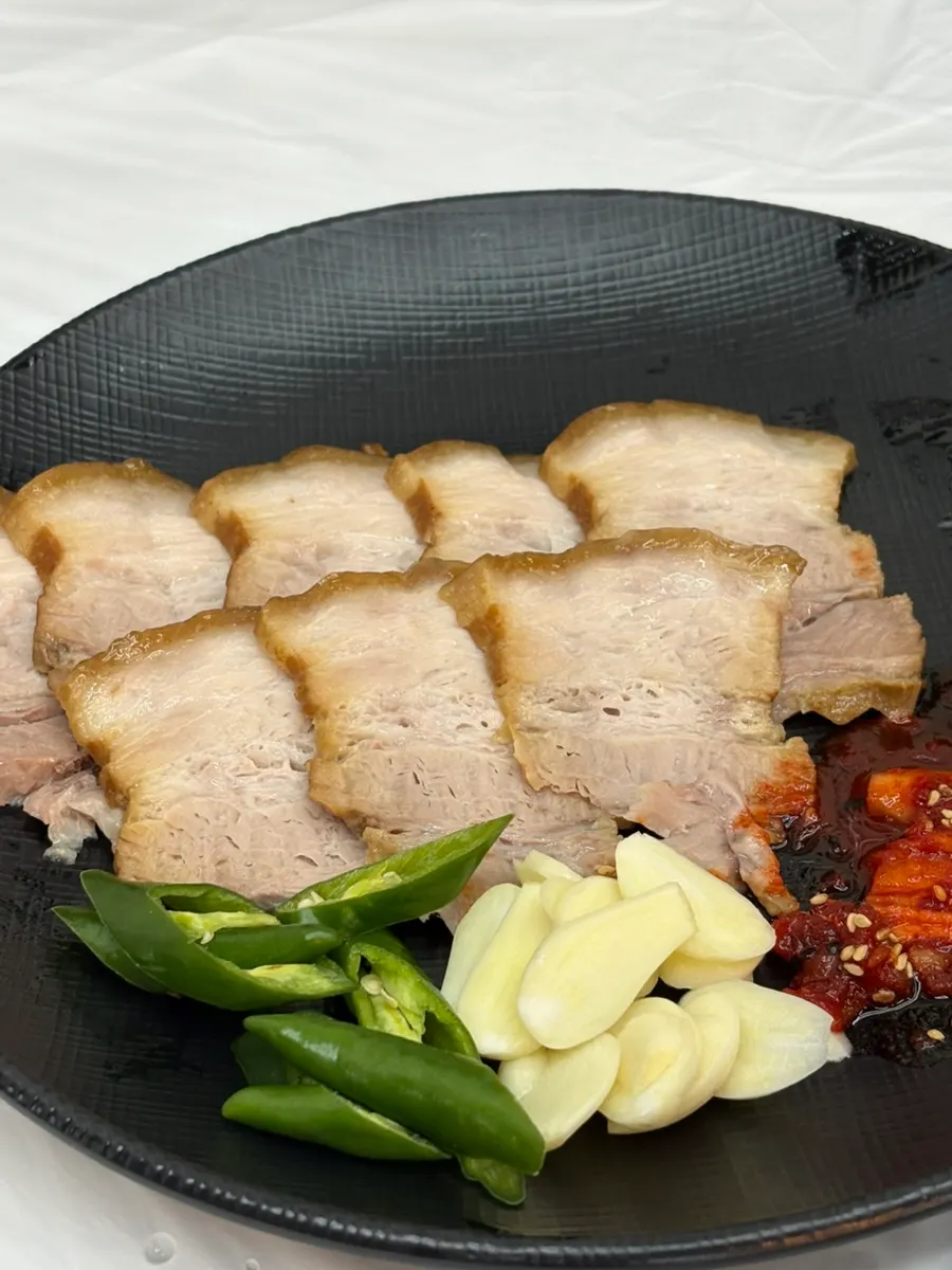 Full spread of two bowls of makguksu, suyuk, and extra pollack sashimi