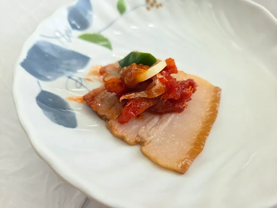 A piece of suyuk topped with pollack sashimi salad