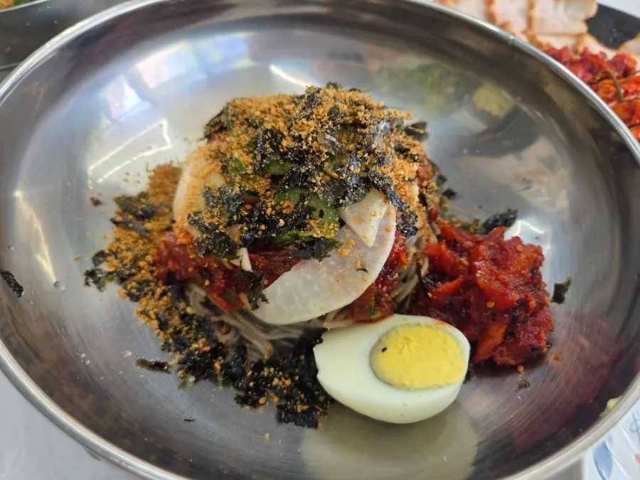 Pollack sashimi makguksu topped with pollack sashimi and seaweed flakes