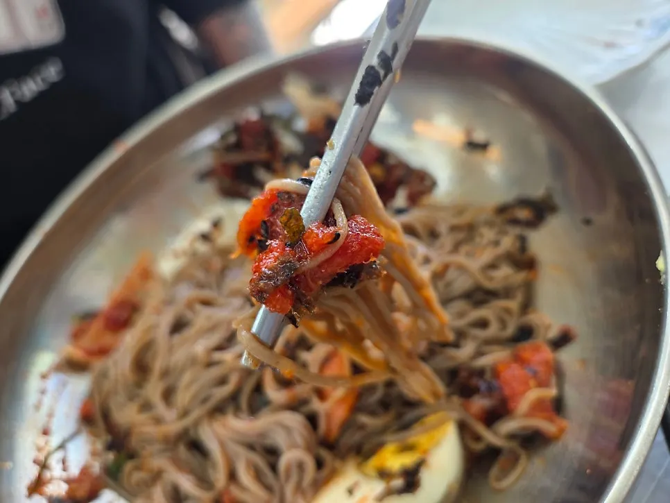 Close-up of makguksu piled high with pollack sashimi