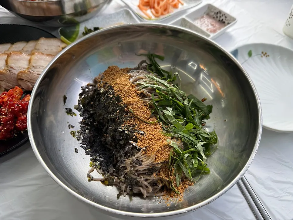 Perilla oil buckwheat makguksu topped with perilla powder, seaweed flakes, and perilla leaves
