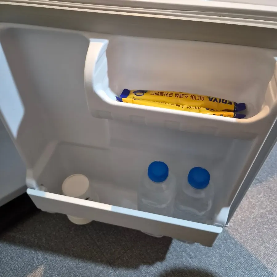Agua embotellada, café instantáneo y vasos de papel en la nevera