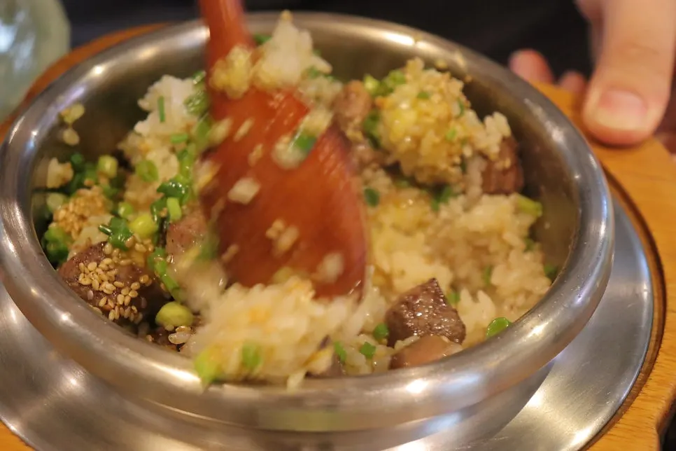 A spoonful of rice topped with a piece of steak