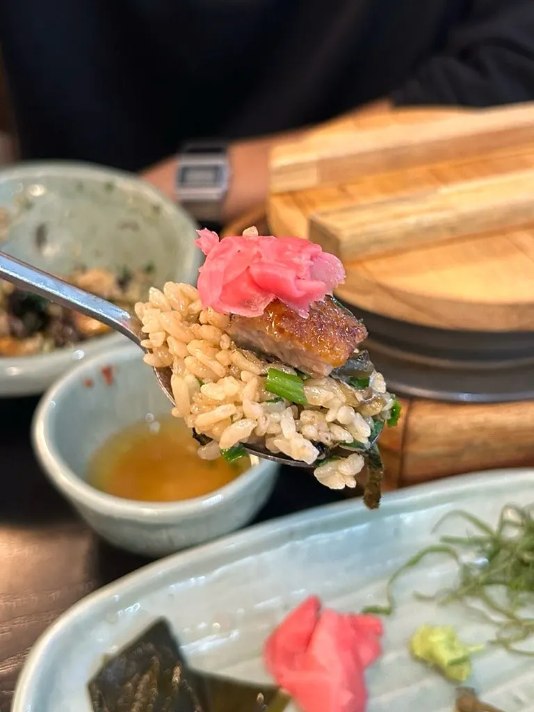 A spoonful of rice topped with eel and shredded perilla leaf