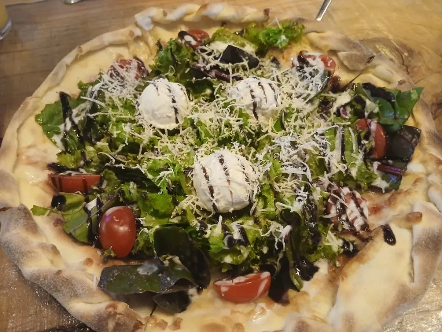 Close-up of the salad pizza drizzled with balsamic sauce