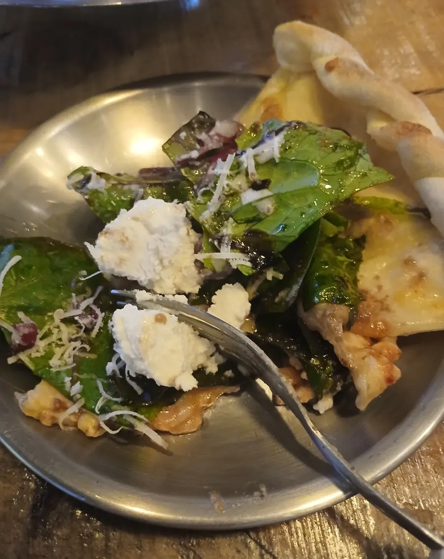 A slice of ricotta cheese salad pizza lifted up