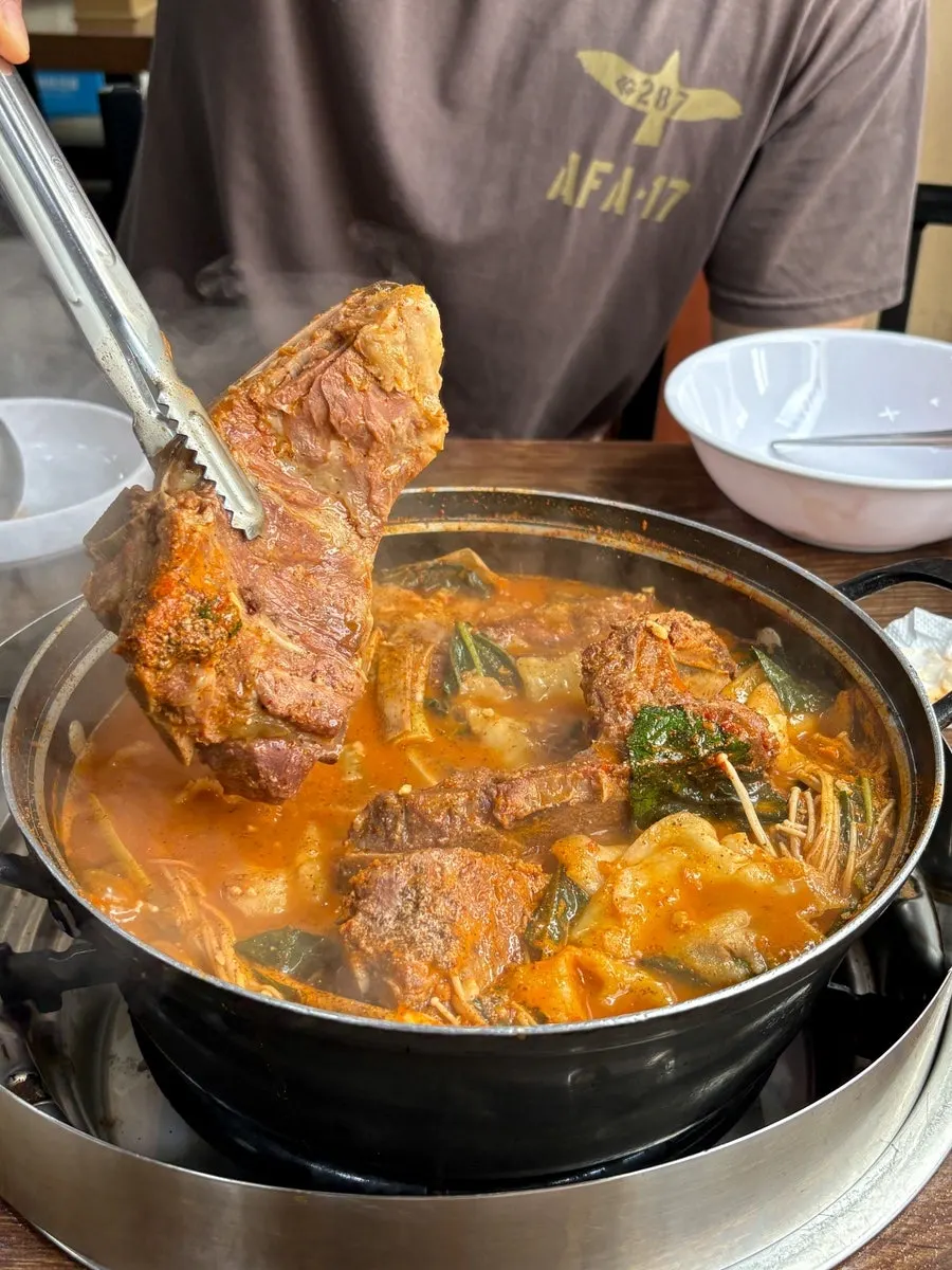 A spoonful of sujebi lifted from the pot
