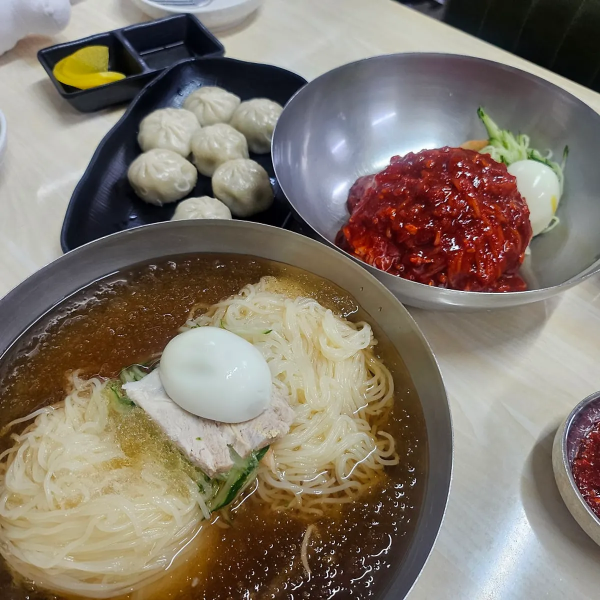 밀면 곱배기와 비빔밀면, 만두가 올려진 상차림