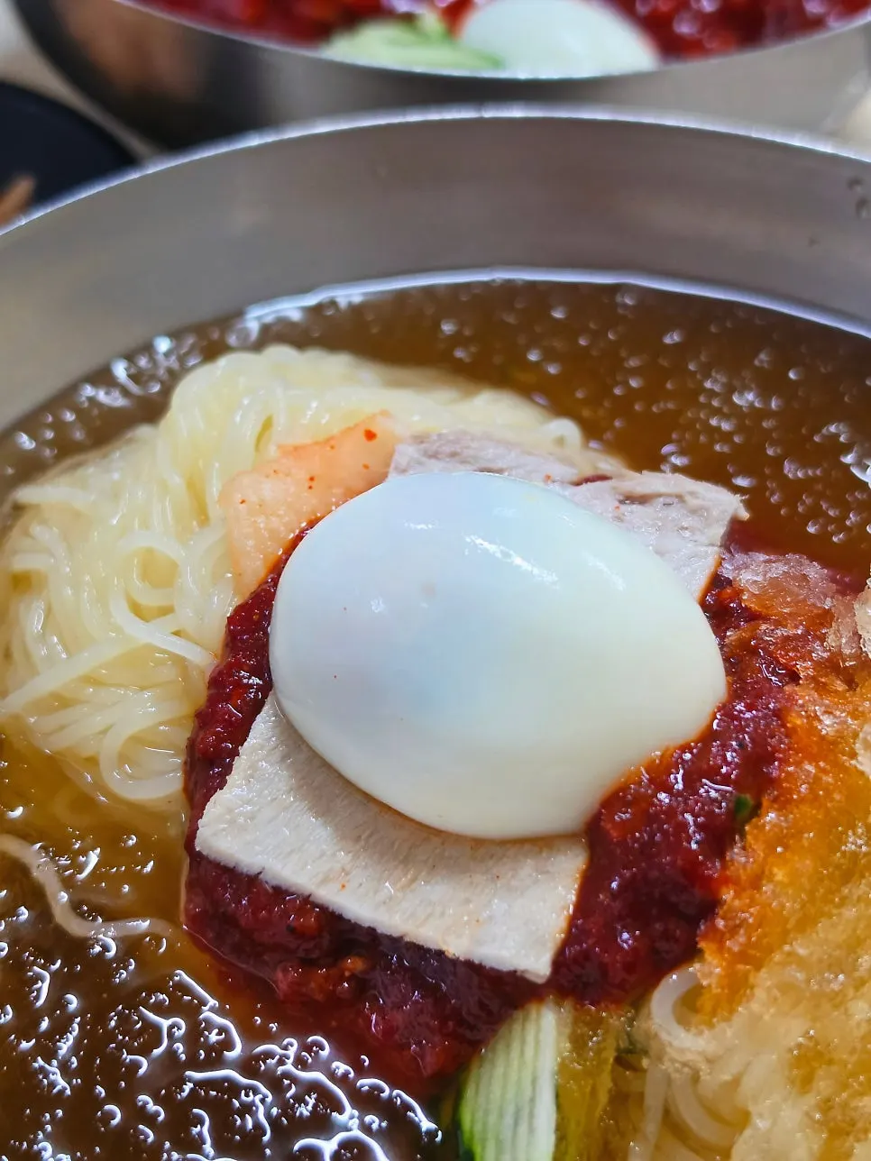 Water milmyeon topped with chili sauce, cucumber, and beef