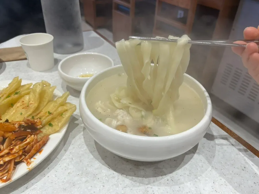 Chicken kalguksu topped with chicken and roasted garlic