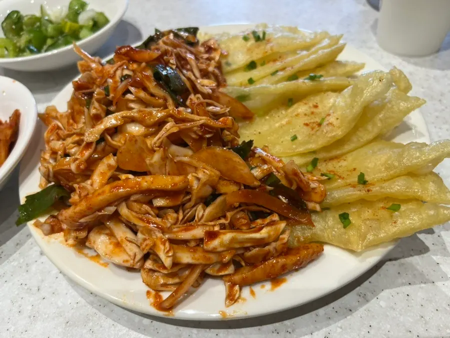 A plate of squid bibim mandu ringed with flat dumplings