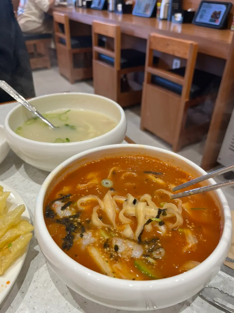 A bite of squid bibim mandu eaten alongside kalguksu