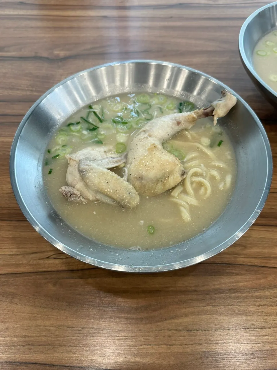 Bowl of dak kalguksu topped with half a chicken