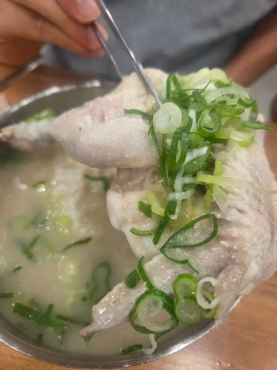 A whole chicken leg lifted with chopsticks