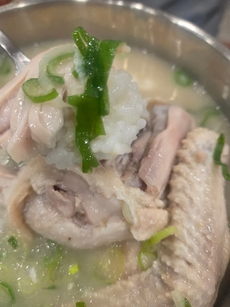 A spoonful of rice topped with chicken meat from the dak gomtang