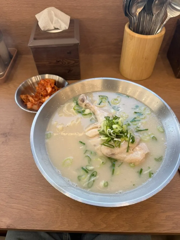 A bowl of extra-large dak kalguksu topped with a whole half chicken