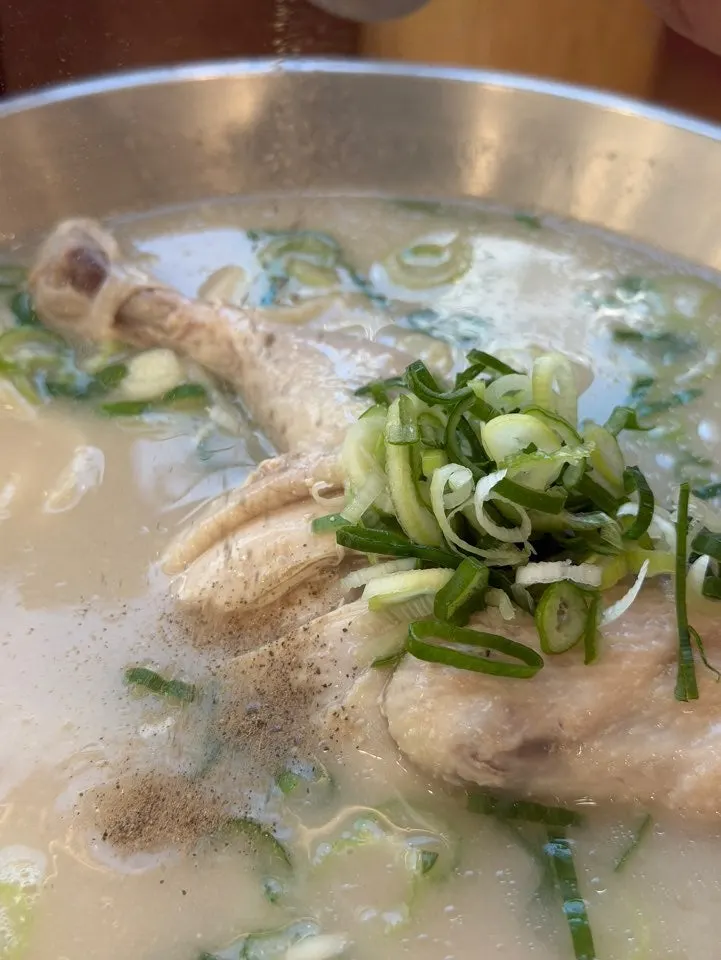 Silver bowl brimming with pale perilla chicken broth