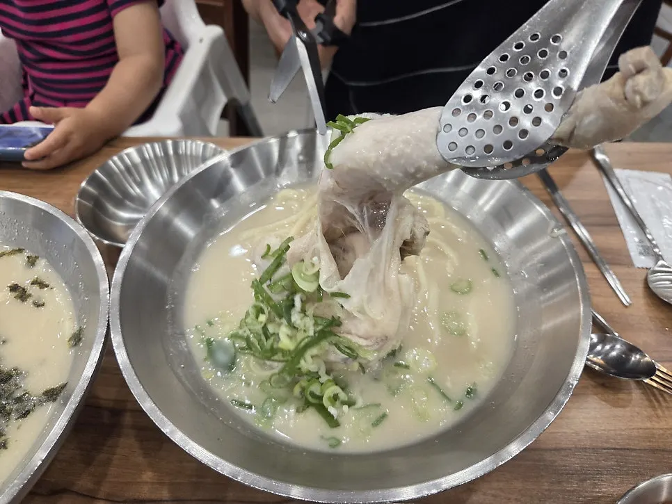 A large chicken leg lifted out of the broth