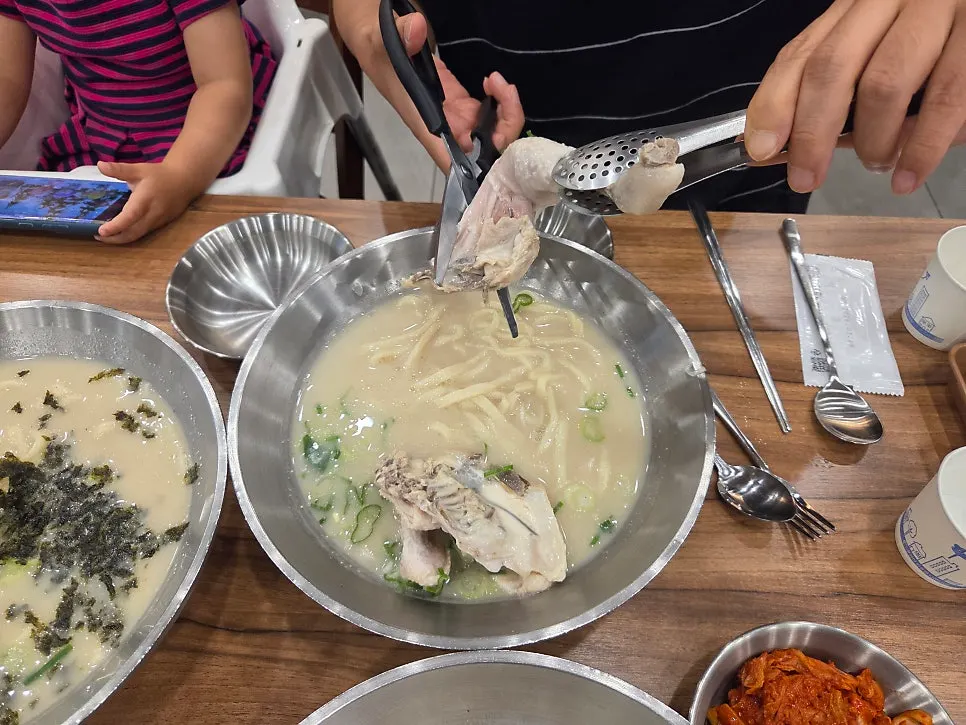 A bowl of dak kalguksu with half a chicken inside