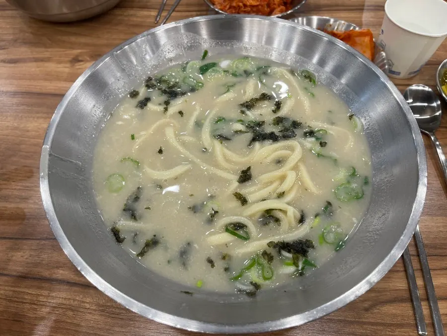 Dak kalguksu with chicken and noodles lifted out of the bowl