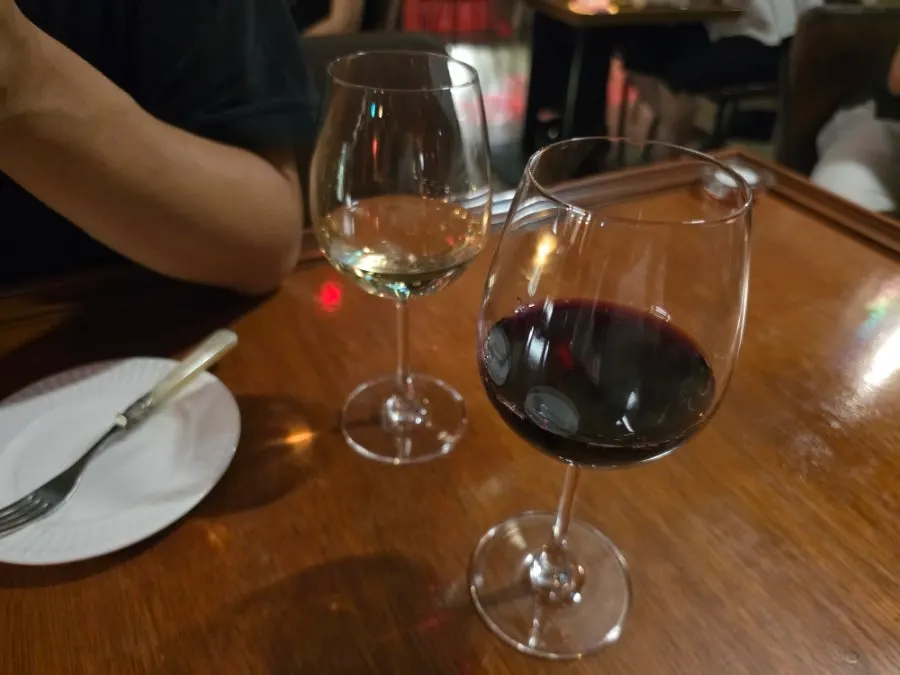 A glass of wine poured by a staff member