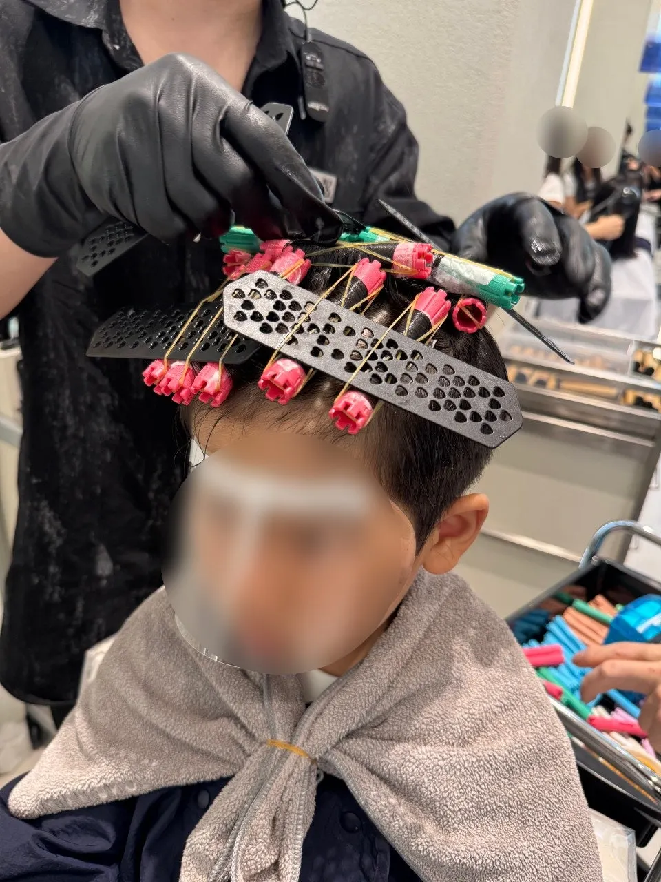 Boy getting rods wrapped for the junior perm
