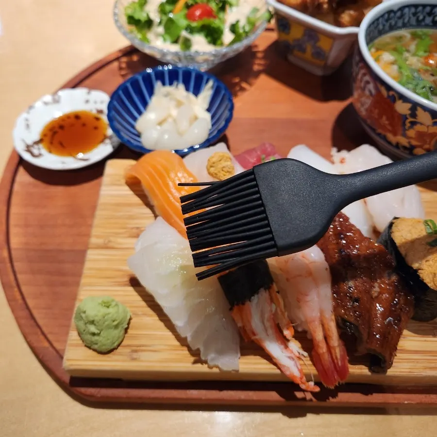 A piece of sushi brushed with soy sauce