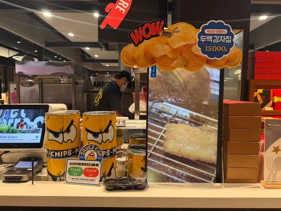 Freshly fried potato chips in a yellow tub
