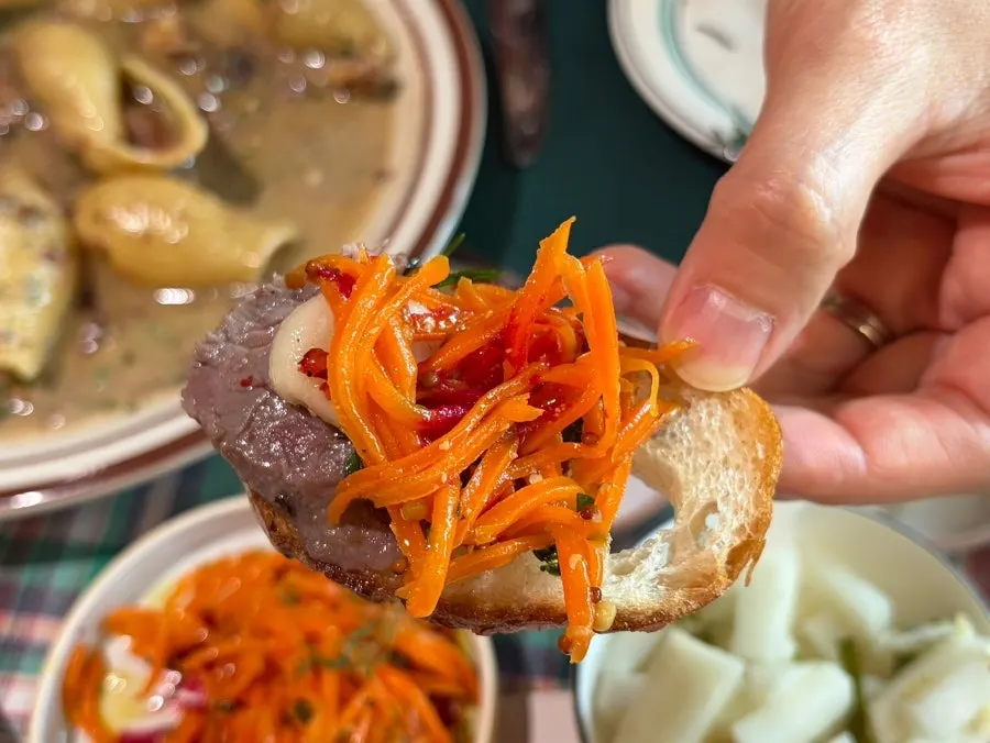 A bite of baguette topped with meat and perilla oil carrot rapée