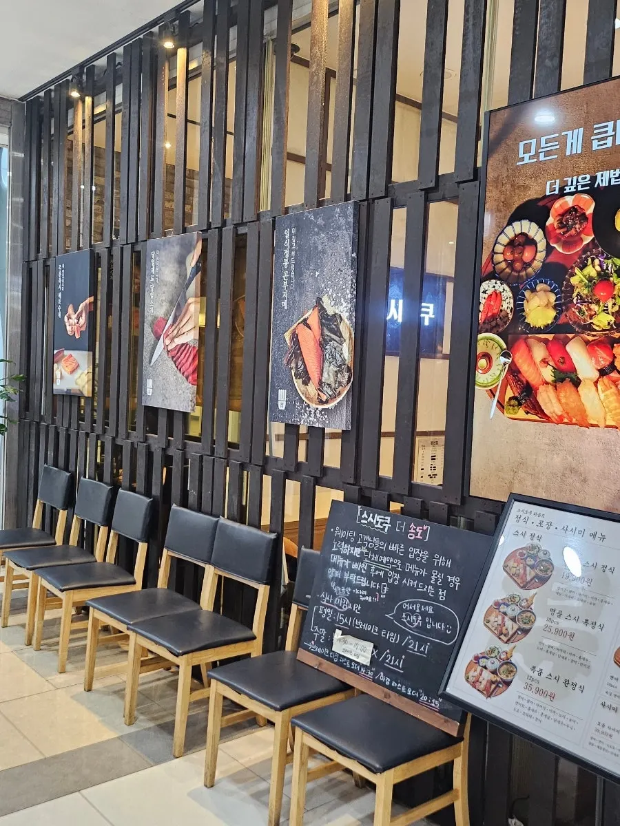 Entrance of Sushi Doku The Songdo with a line forming in the evening