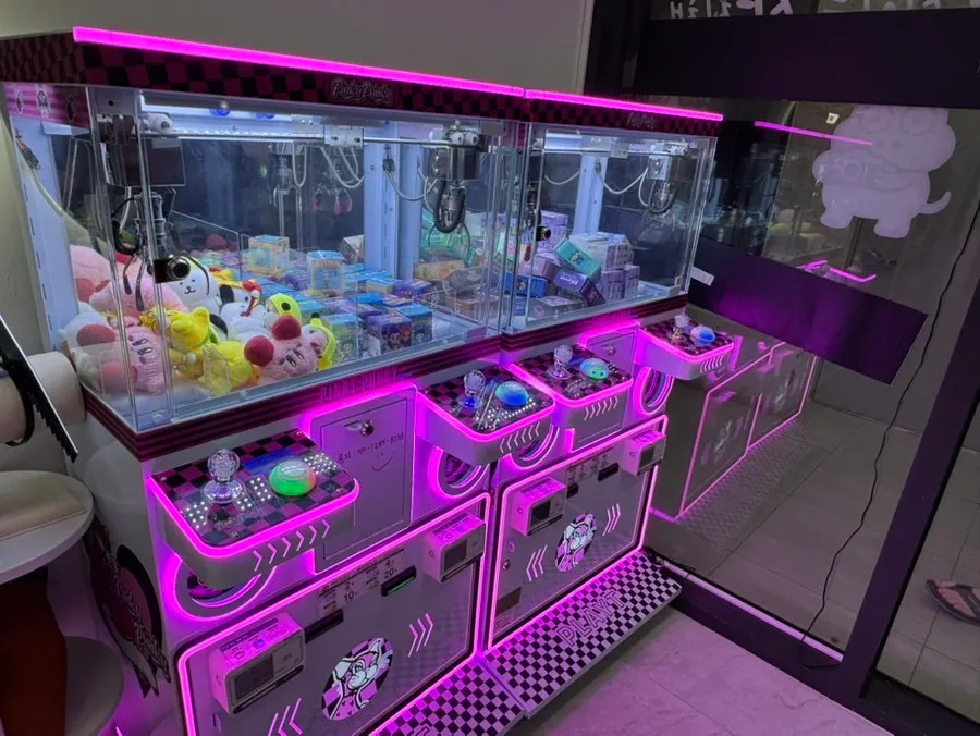 Gacha machine with character goods lit up in pink lighting