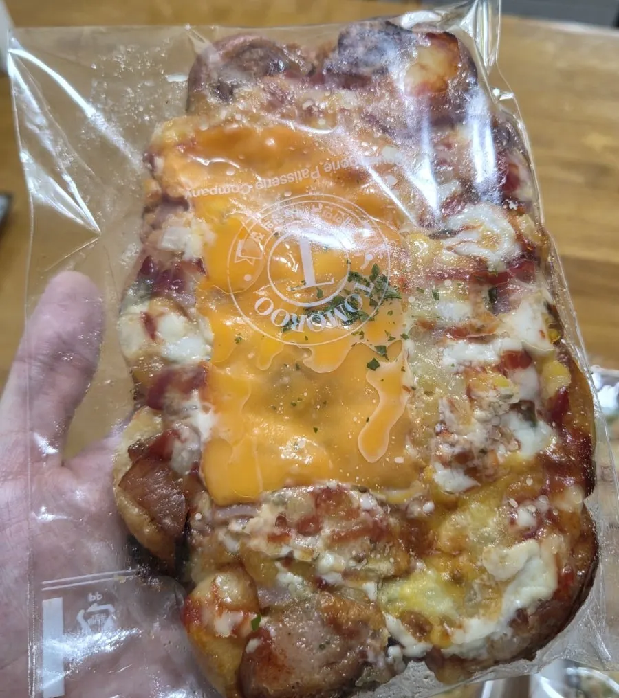 A large pizza bread covered in cheddar cheese