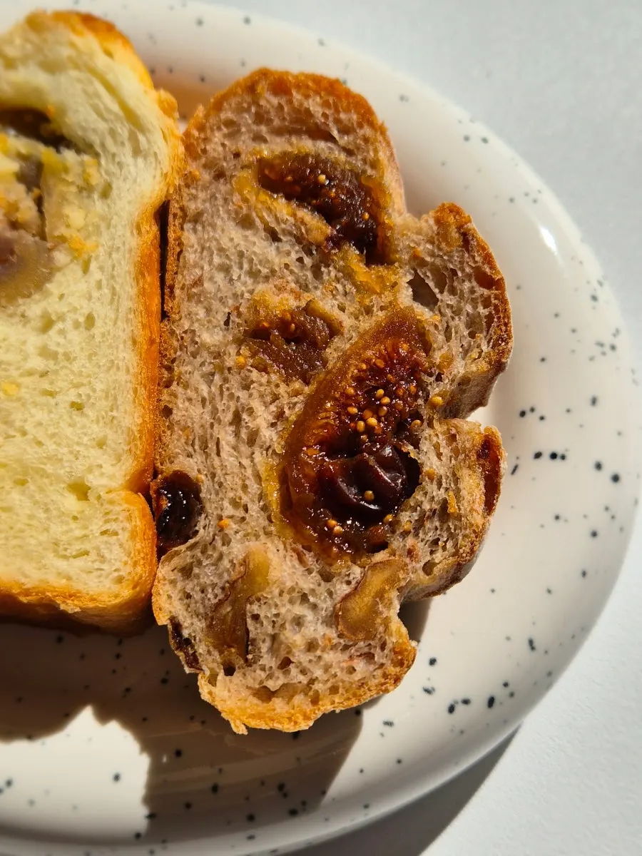 Cross-section of chestnut bread with large chestnut pieces, next to rye fig bread