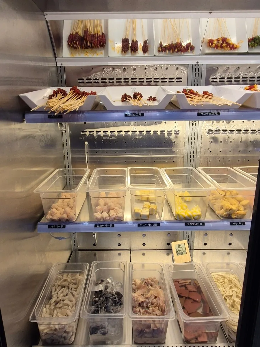 Self-serve fridge with vegetables, rice cakes, and glass noodles